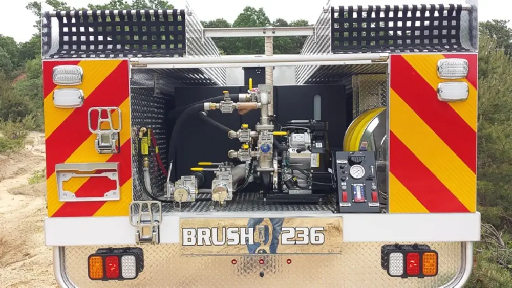 Exterior view of small fire truck showing cab, body compartments, and wheel/tire area.