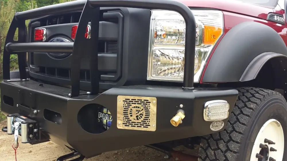 Exterior view of small fire truck showing cab, body compartments, and wheel/tire area.