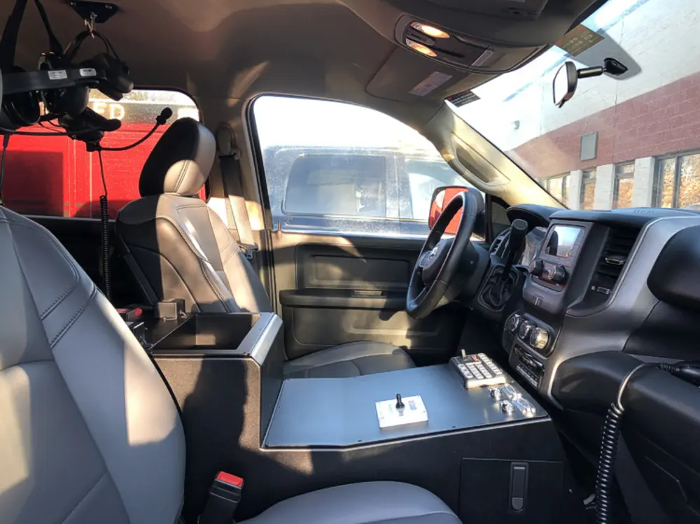 Exterior view of small fire truck showing cab, body compartments, and wheel/tire area.