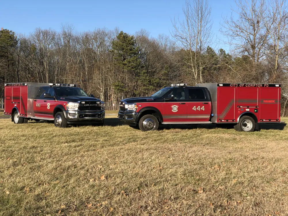 Exterior view of small fire truck showing cab, body compartments, and wheel/tire area.