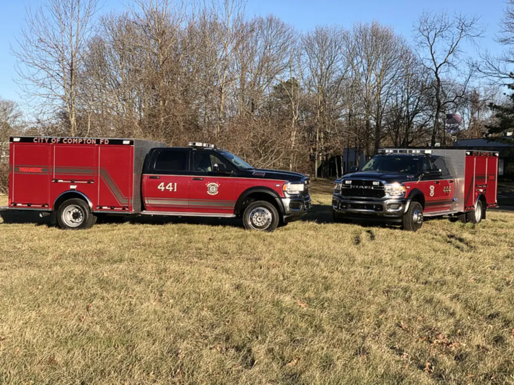 Exterior view of small fire truck showing cab, body compartments, and wheel/tire area.