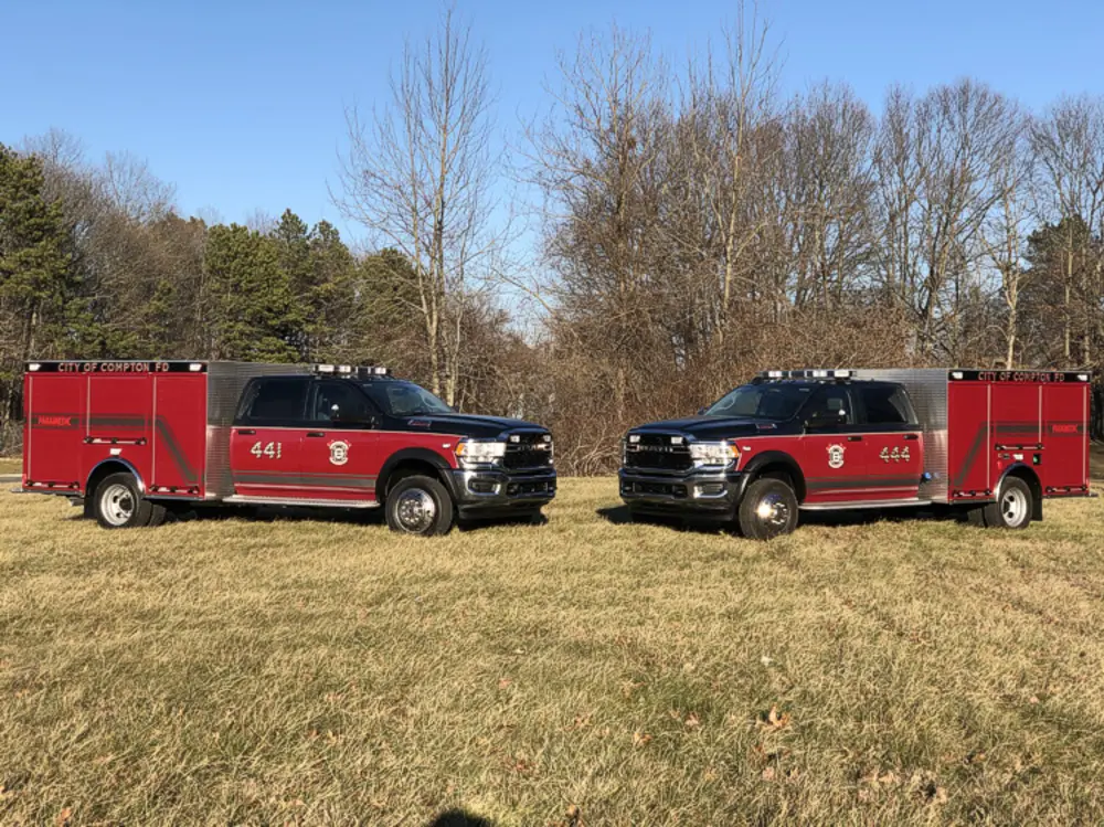 Exterior view of small fire truck showing cab, body compartments, and wheel/tire area.