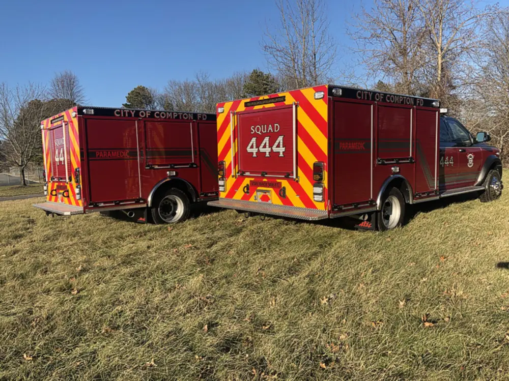 Exterior view of small fire truck showing cab, body compartments, and wheel/tire area.