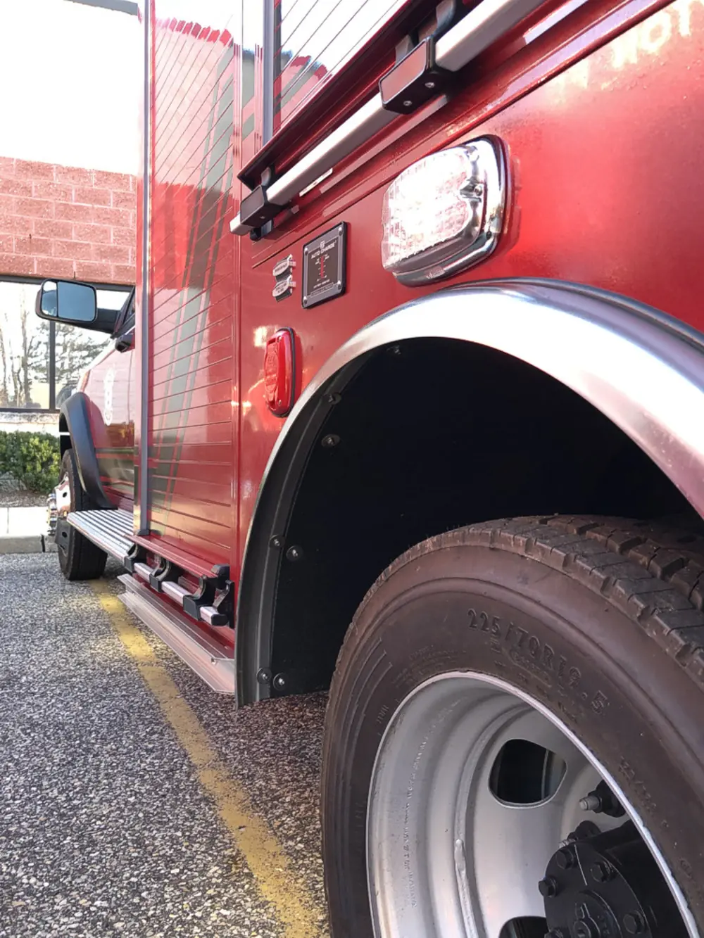 Exterior view of small fire truck showing cab, body compartments, and wheel/tire area.