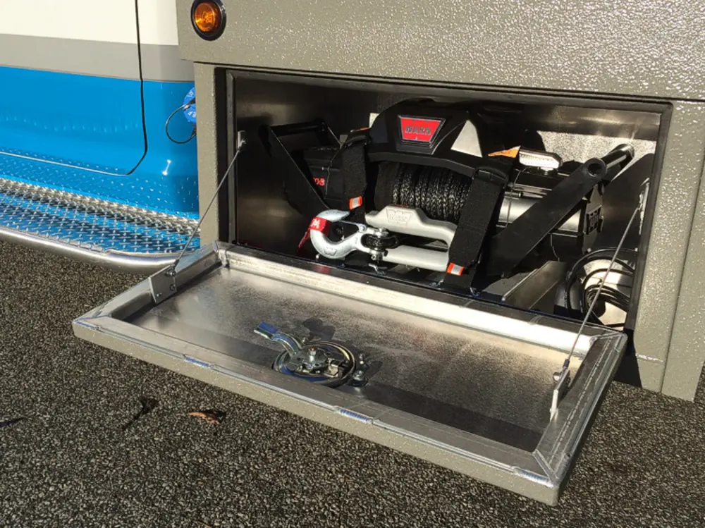 Exterior view of small fire truck showing cab, body compartments, and wheel/tire area.