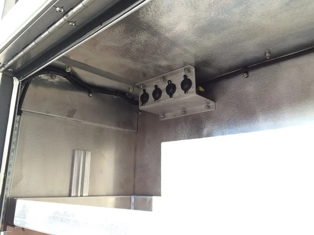 Exterior view of small fire truck showing cab, body compartments, and wheel/tire area.