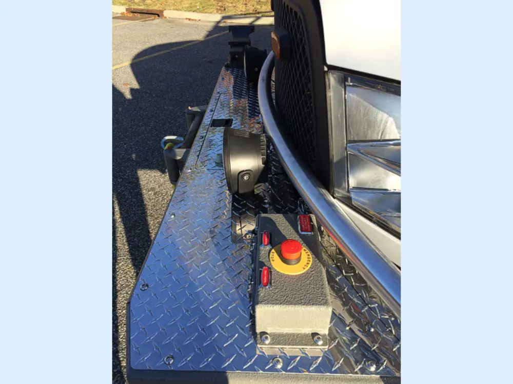 Exterior view of small fire truck showing cab, body compartments, and wheel/tire area.