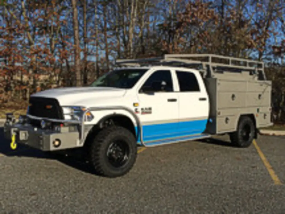 Exterior view of small fire truck showing cab, body compartments, and wheel/tire area.