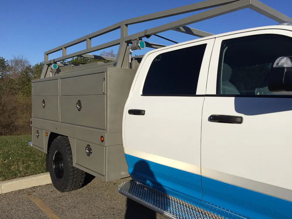Exterior view of small fire truck showing cab, body compartments, and wheel/tire area.