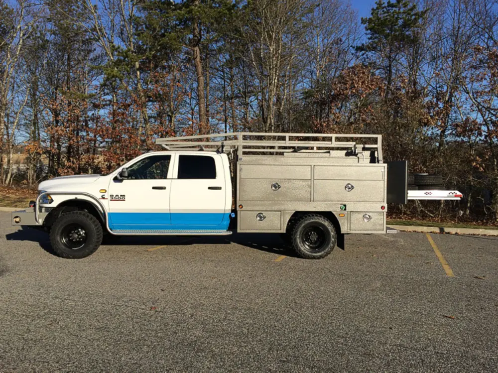 Exterior view of small fire truck showing cab, body compartments, and wheel/tire area.