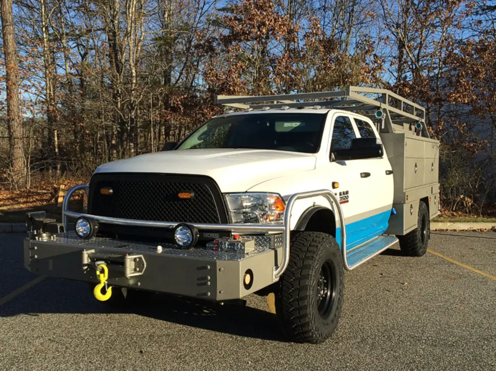 Exterior view of small fire truck showing cab, body compartments, and wheel/tire area.