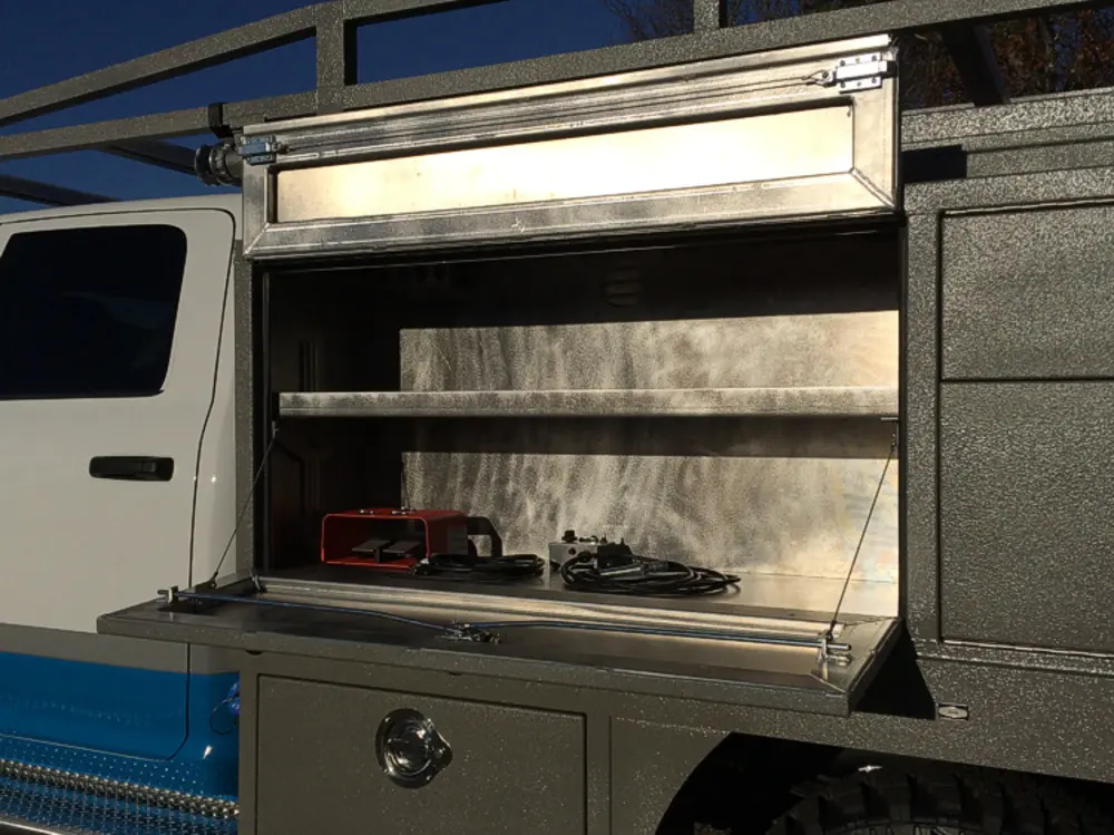 Exterior view of small fire truck showing cab, body compartments, and wheel/tire area.