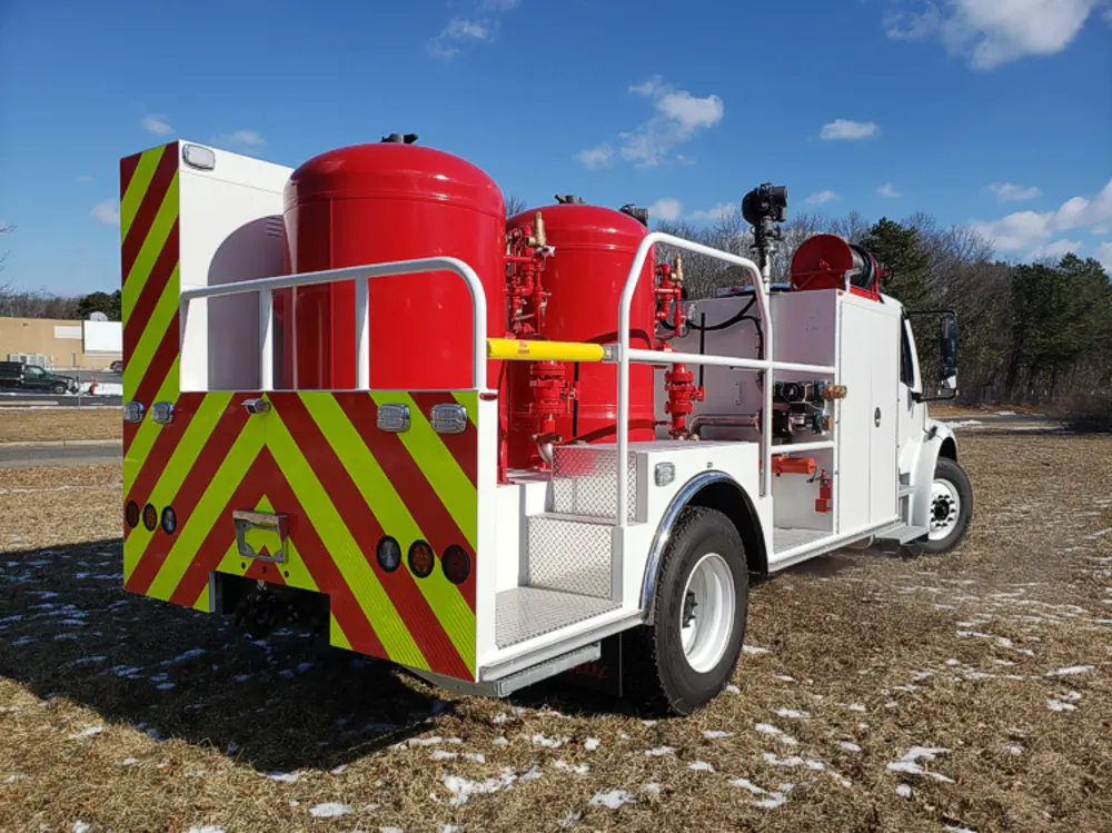 Exterior view of small fire truck showing cab, body compartments, and wheel/tire area.