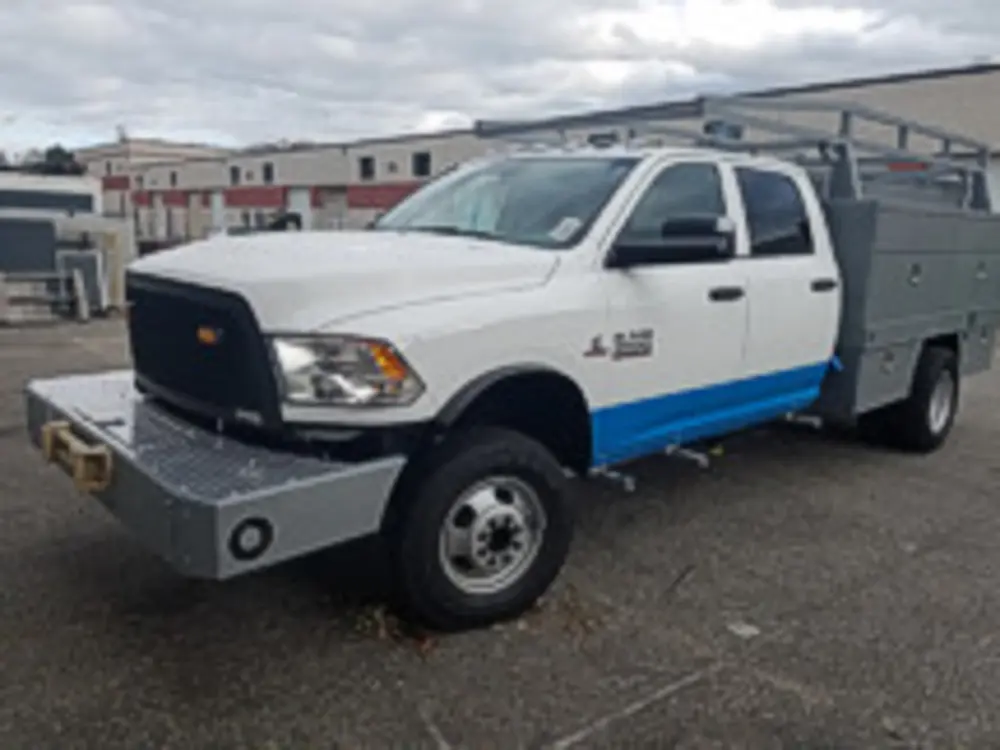 Exterior view of small fire truck showing cab, body compartments, and wheel/tire area.