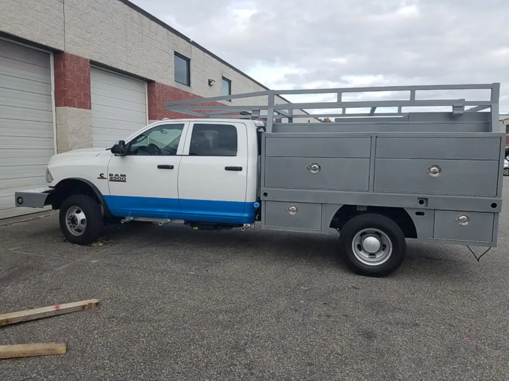 Exterior view of small fire truck showing cab, body compartments, and wheel/tire area.