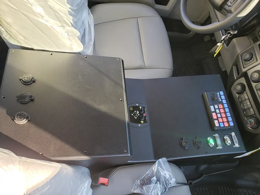 Exterior view of small fire truck showing cab, body compartments, and wheel/tire area.