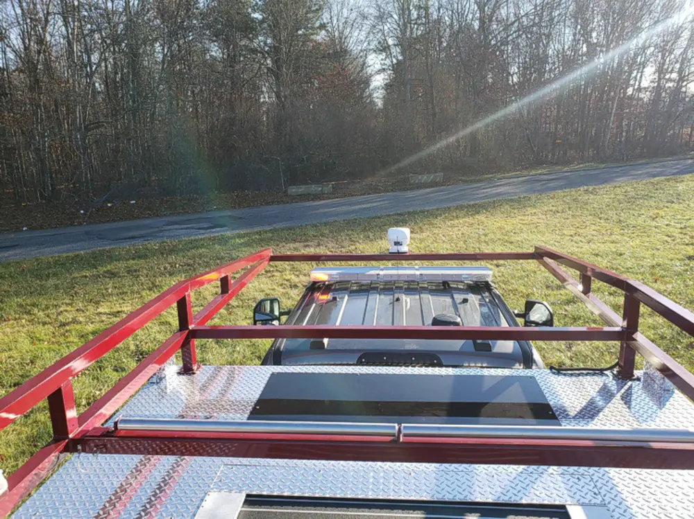 Exterior view of small fire truck showing cab, body compartments, and wheel/tire area.