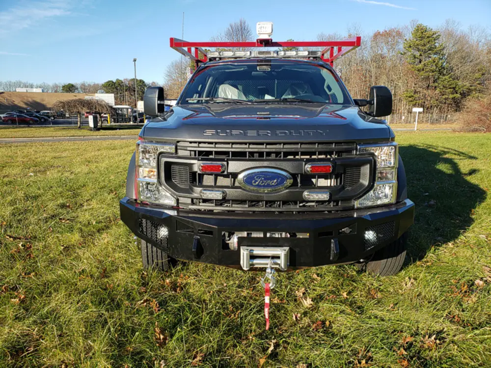 Exterior view of small fire truck showing cab, body compartments, and wheel/tire area.