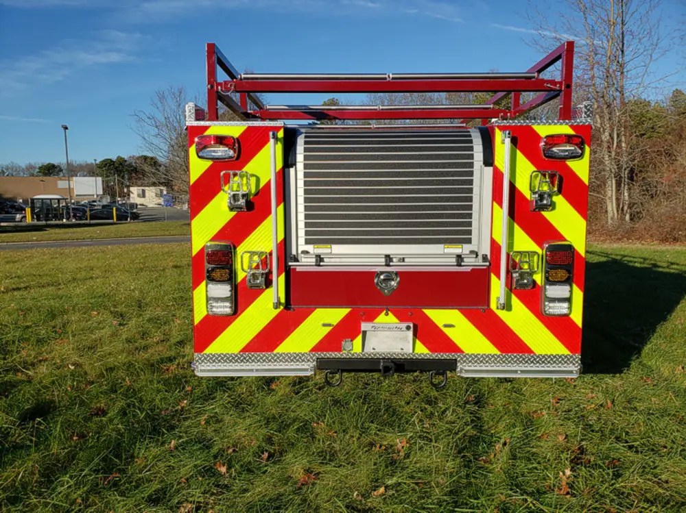Exterior view of small fire truck showing cab, body compartments, and wheel/tire area.