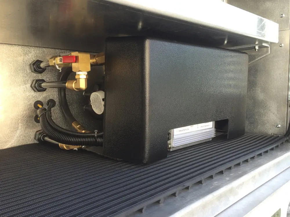 Exterior view of small fire truck showing cab, body compartments, and wheel/tire area.