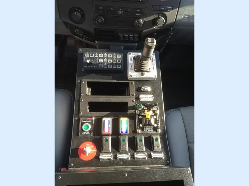 Exterior view of small fire truck showing cab, body compartments, and wheel/tire area.