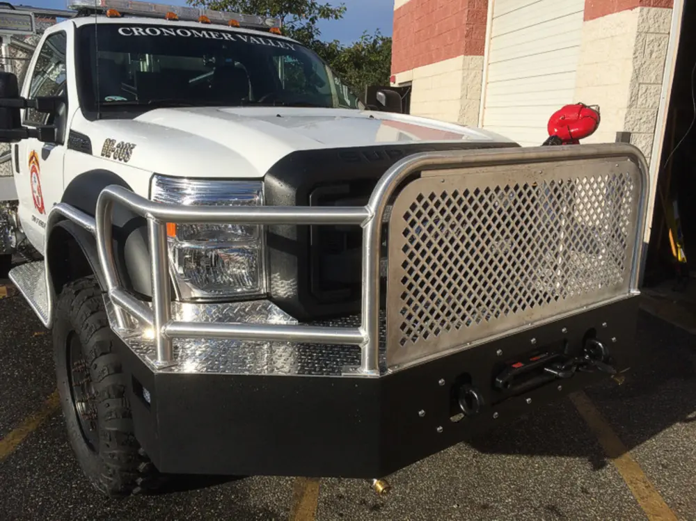 Exterior view of small fire truck showing cab, body compartments, and wheel/tire area.