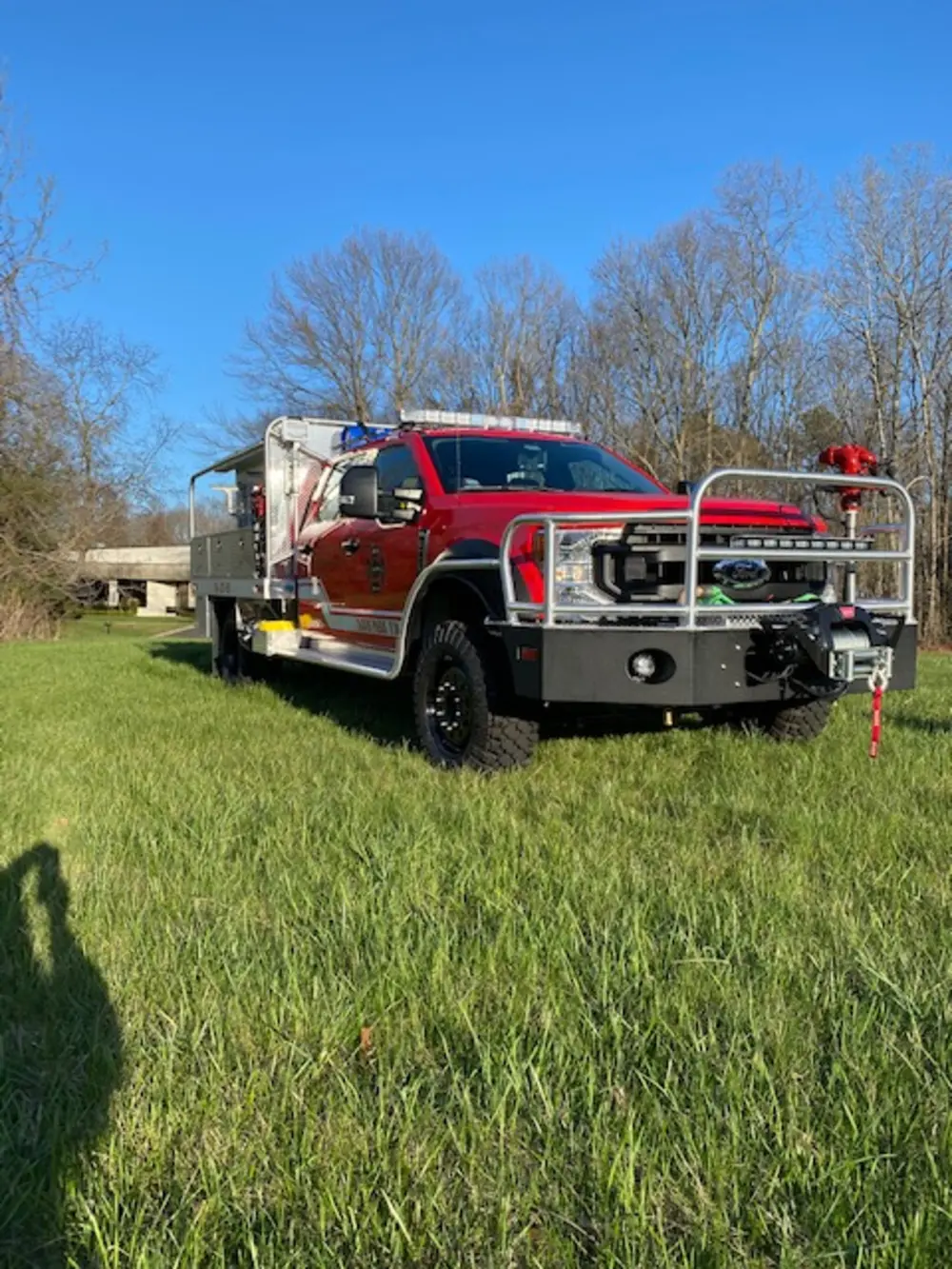 Exterior view of small fire truck showing cab, body compartments, and wheel/tire area.