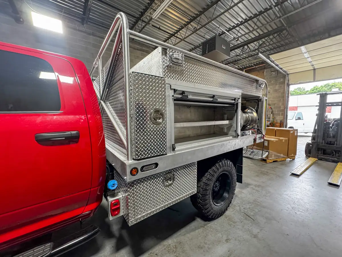 Right-rear side view showing the open side compartment, hose reel bay, and rear wheel area.