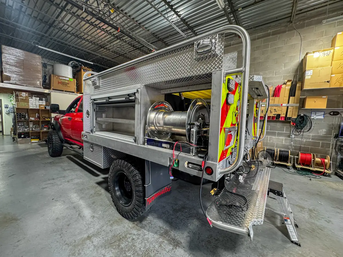 Rear-right view of the truck body showing the hose reel bay, rear step, and open rear section.