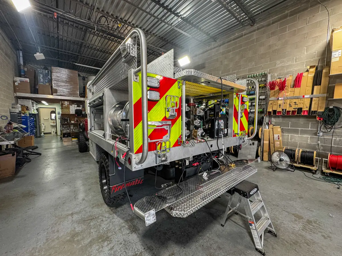 Rear view with both rear doors open showing the pump panel, valves, gauges, and rear step platform.