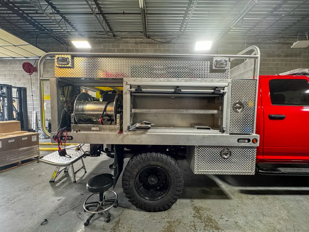 Left-side profile of the utility body showing the open side shelf compartment and rear hose reel bay.