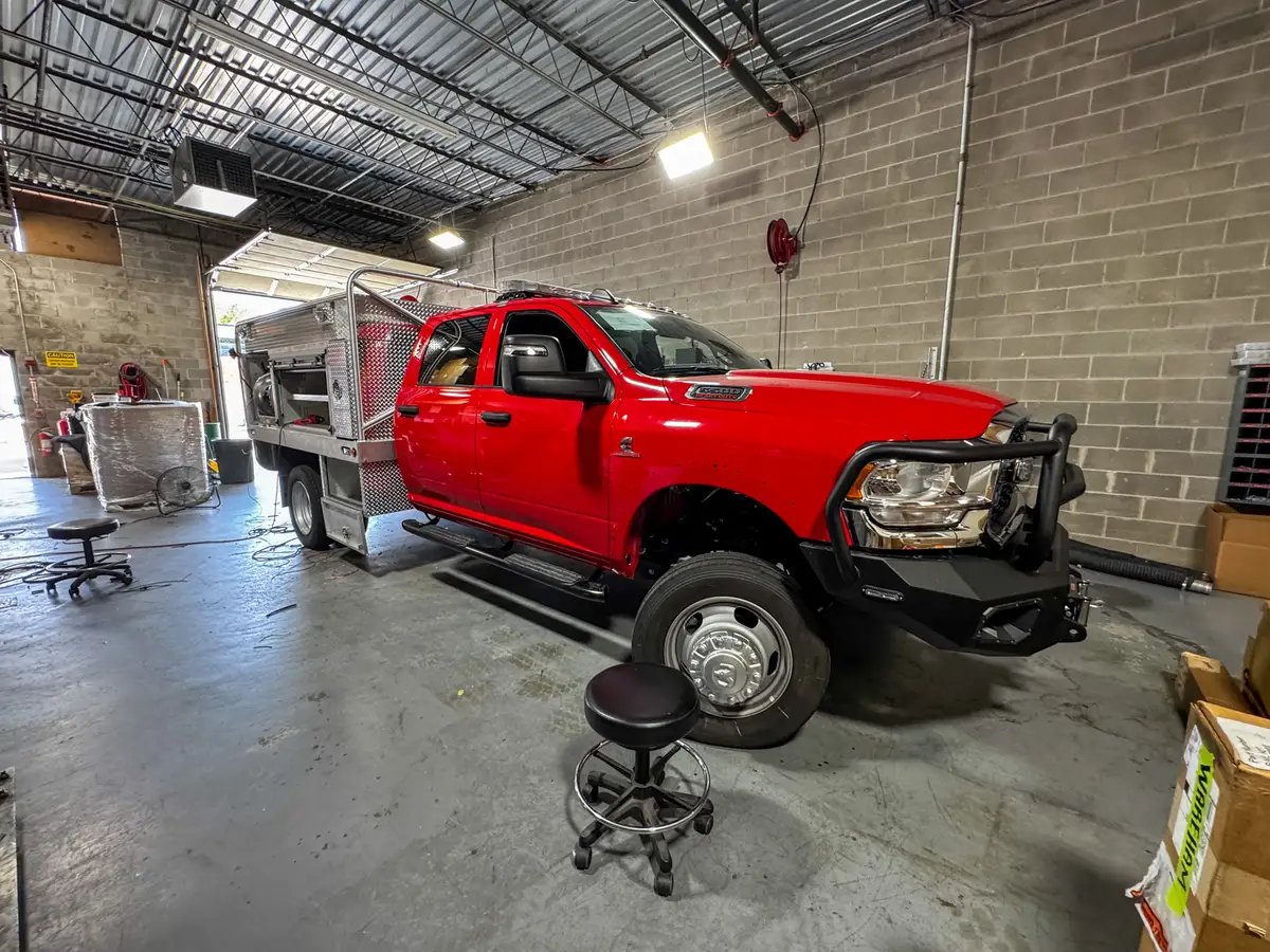 Front-left side view showing the dually front wheel area, cab doors, and utility body behind the cab.
