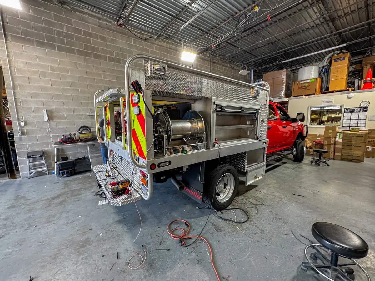 Rear-left angle showing the hose reel bay, open rear section, and lower rear step.