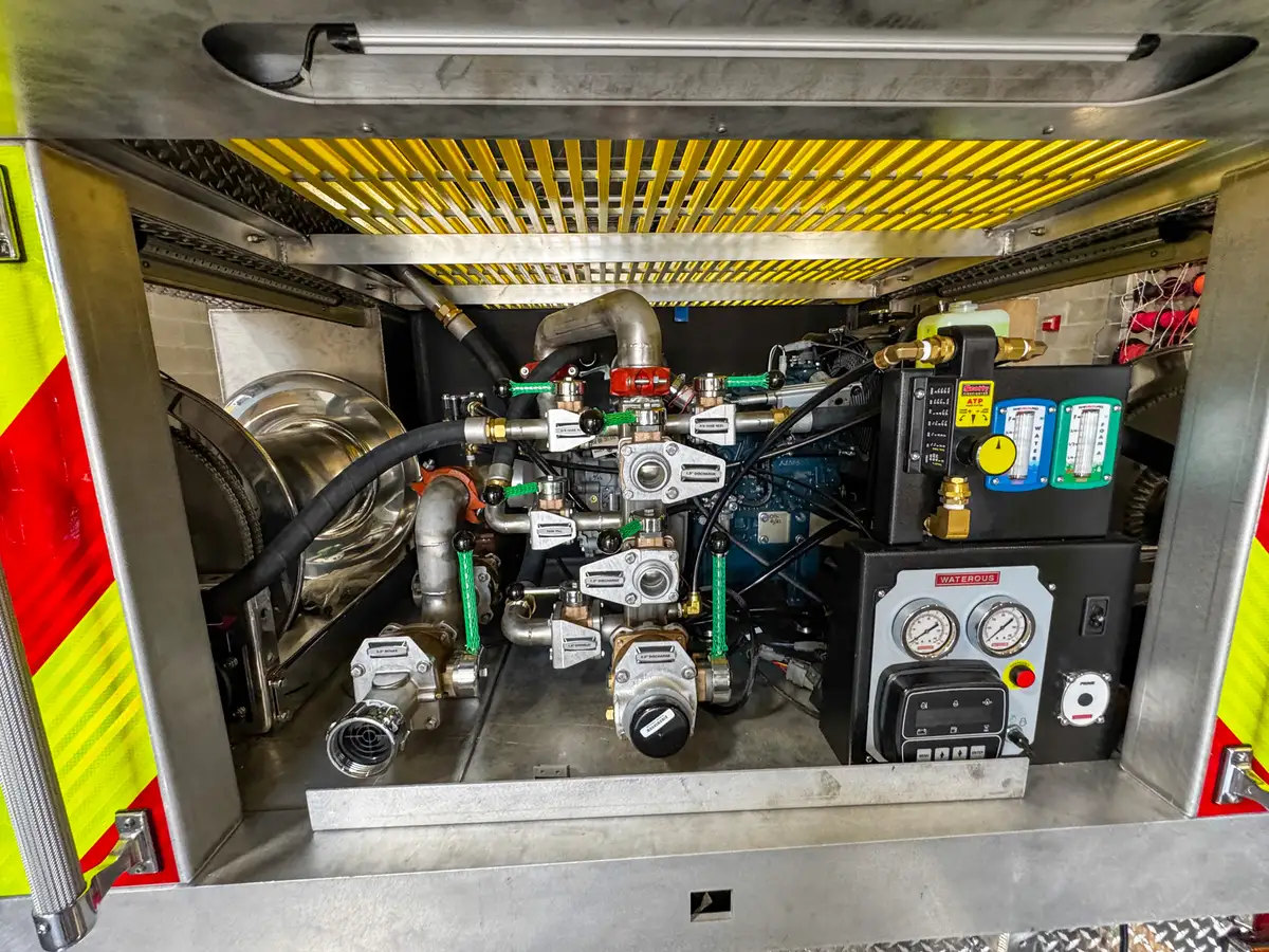 Pump panel close-up showing valves, gauge cluster, flow controls, and connected plumbing.