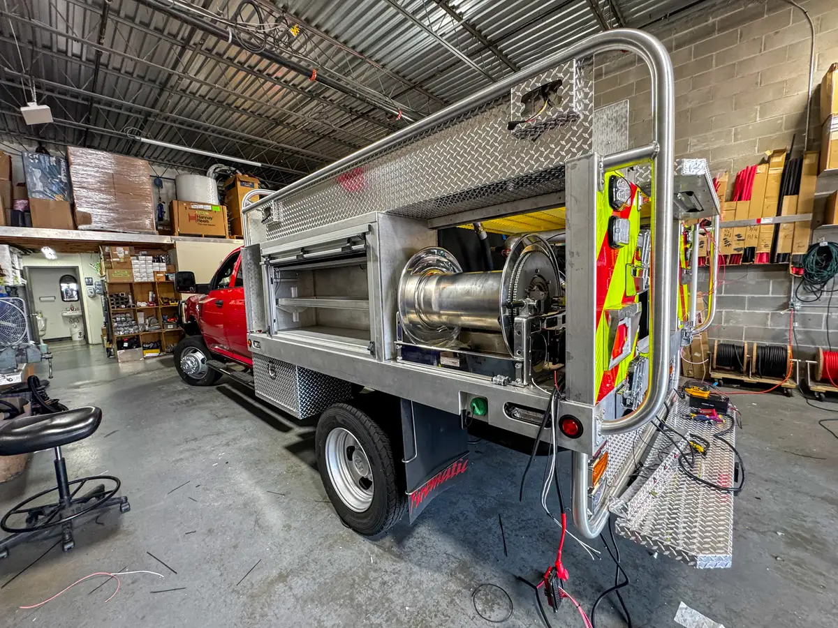Rear-left exterior view showing the side shelf compartment, hose reel bay, and rear corner lighting.