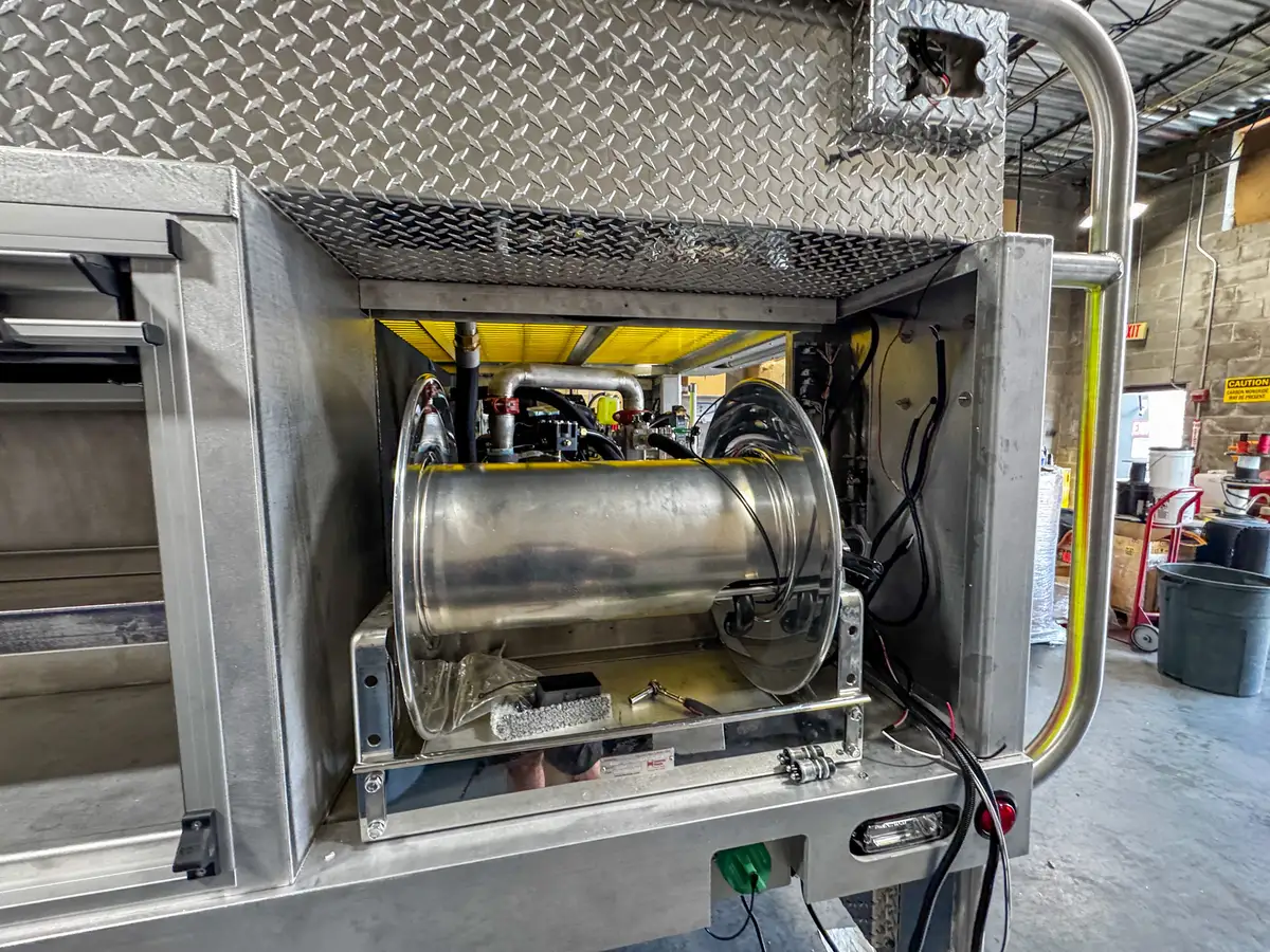 Close side view of the hose reel drum inside the rear-side compartment opening.