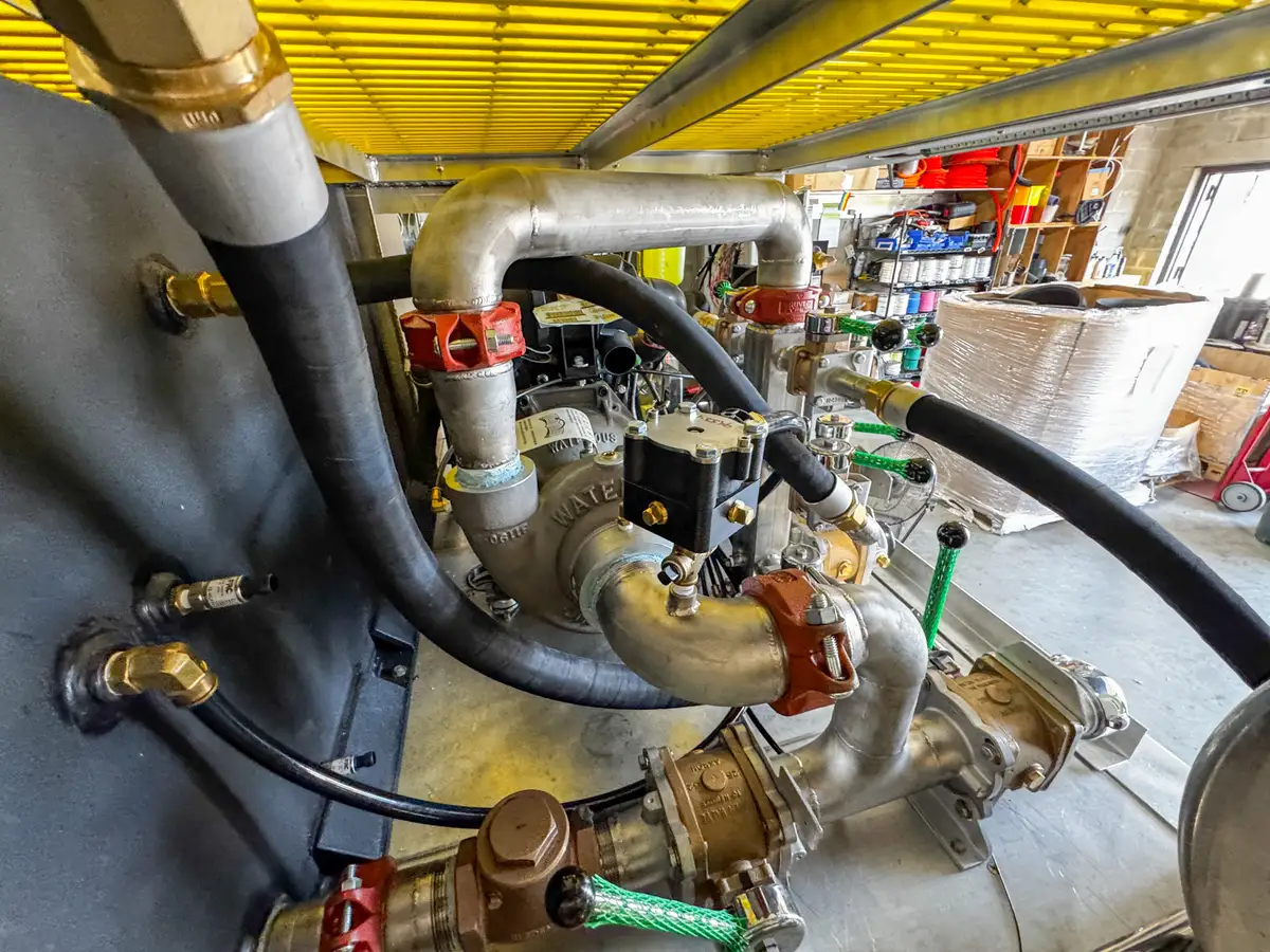 Close-up of pump plumbing and valve components mounted behind the rear compartment area.