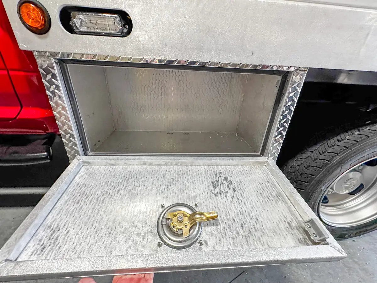 Lower side compartment open above the rear wheel area, showing the box interior and latch hardware.
