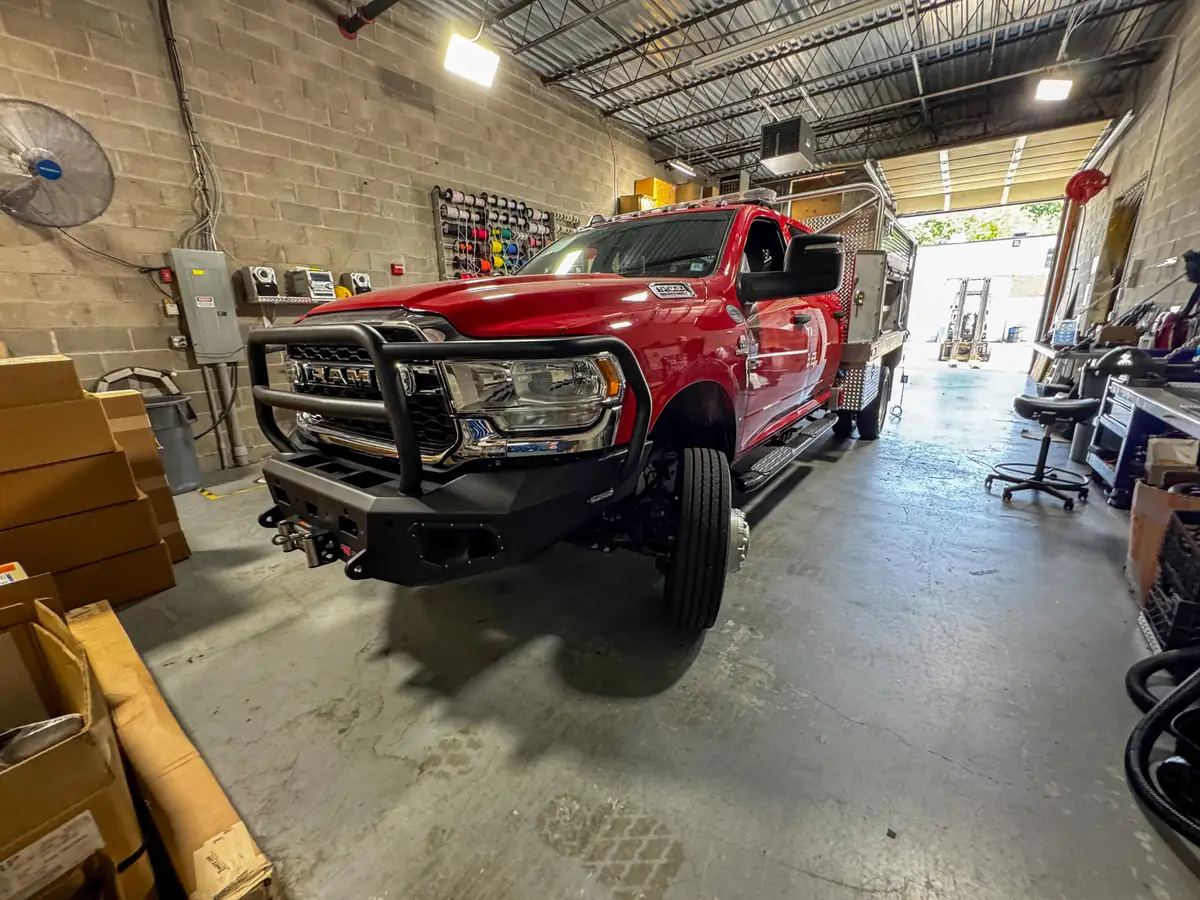 Front-left angle of the truck showing grille guard, bumper, and side body with an open compartment door.