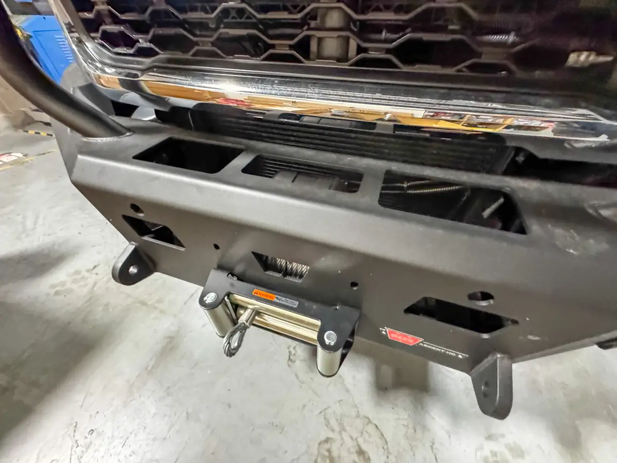 Close-up of the front bumper and winch area beneath the grille guard.
