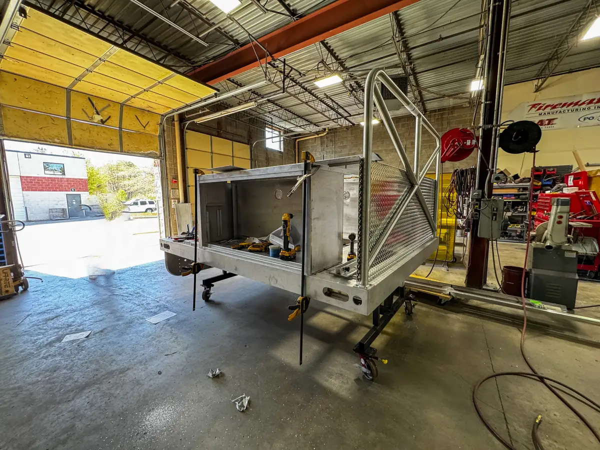 Front-right angle of the unfinished body module showing open compartment structure and side rails.