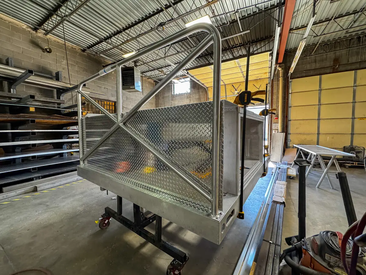 Rear-corner angle of the unfinished body module showing cross-braced rear rails and side paneling.