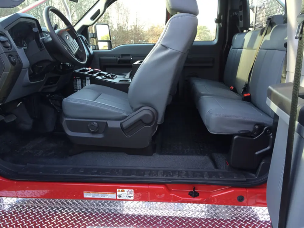 Exterior view of small fire truck showing cab, body compartments, and wheel/tire area.
