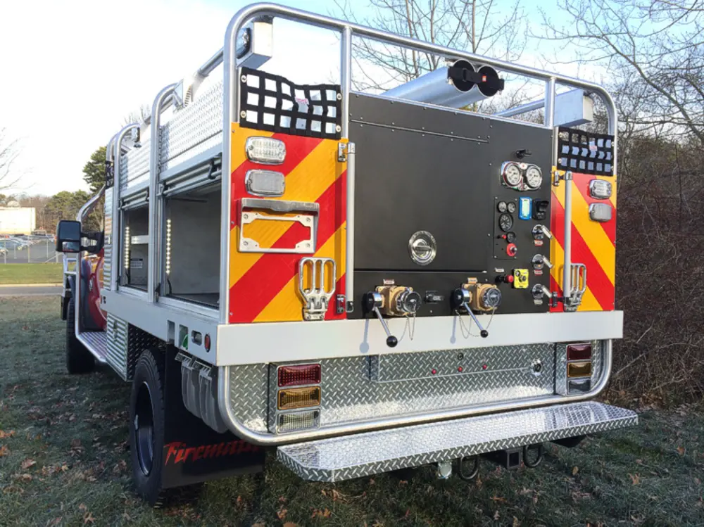 Exterior view of small fire truck showing cab, body compartments, and wheel/tire area.