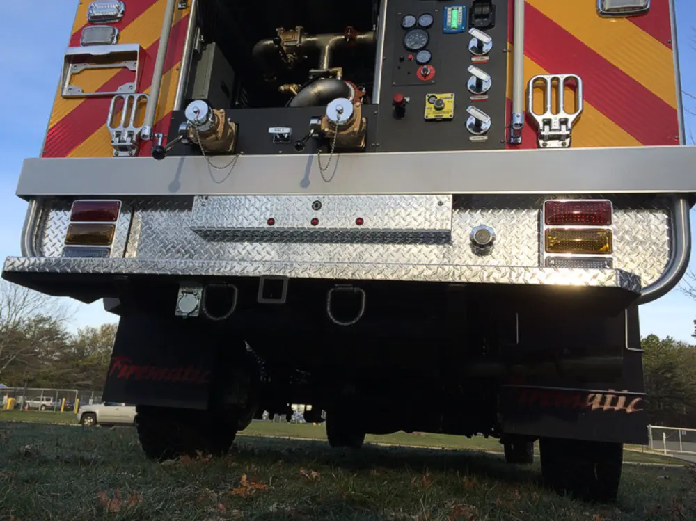 Exterior view of small fire truck showing cab, body compartments, and wheel/tire area.