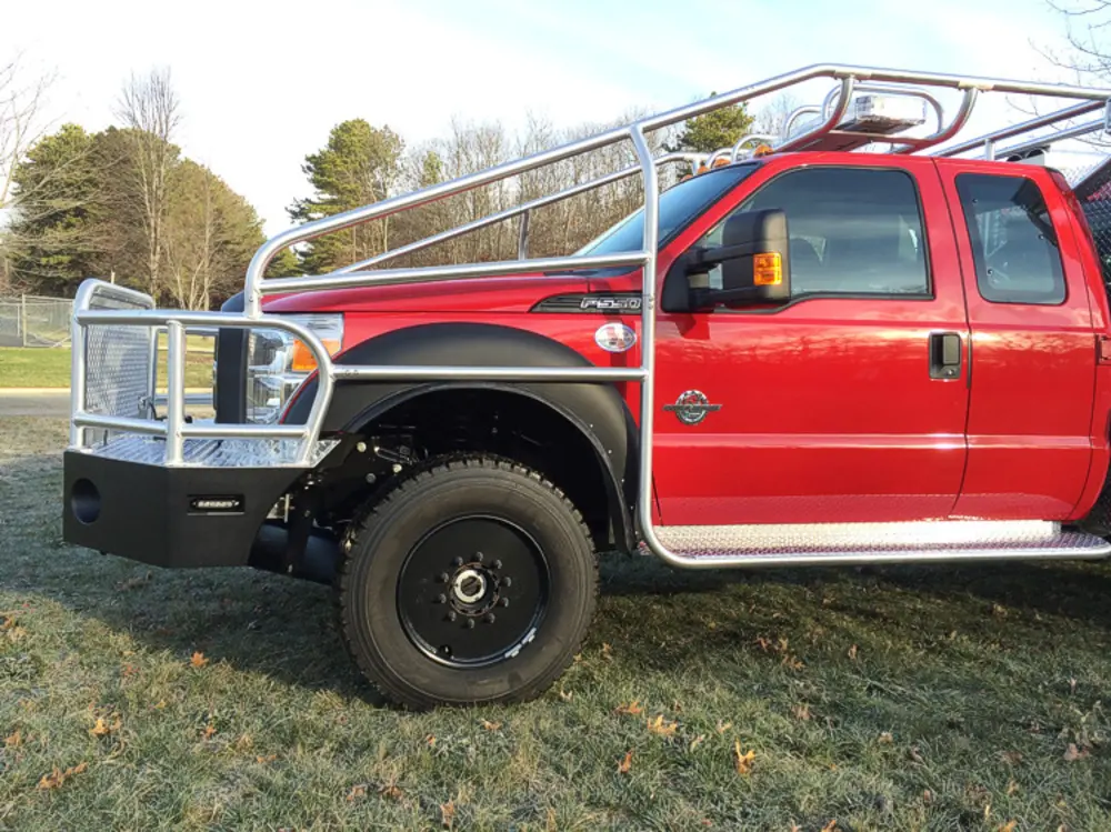 Exterior view of small fire truck showing cab, body compartments, and wheel/tire area.