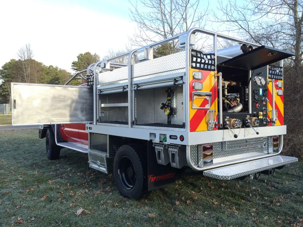 Exterior view of small fire truck showing cab, body compartments, and wheel/tire area.