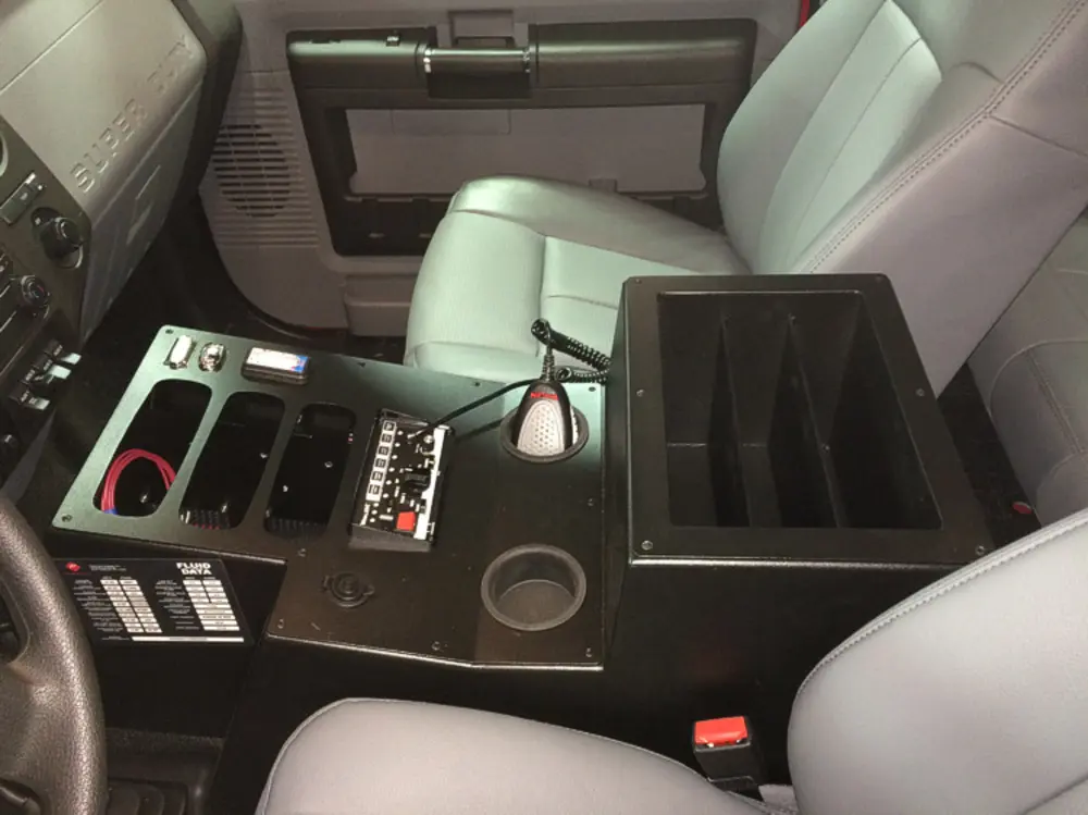 Exterior view of small fire truck showing cab, body compartments, and wheel/tire area.