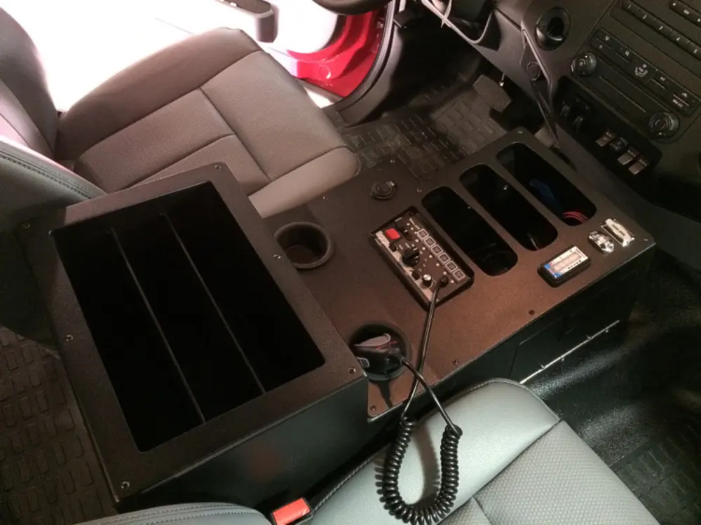 Exterior view of small fire truck showing cab, body compartments, and wheel/tire area.