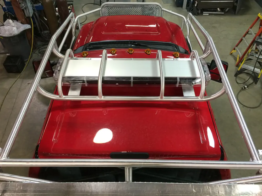 Exterior view of small fire truck showing cab, body compartments, and wheel/tire area.